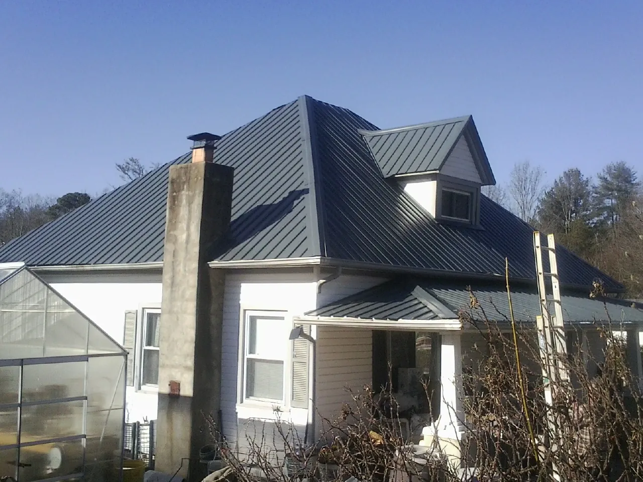 Dark blue standing seam metal roof on a white farmhouse with dormer — Slate & Tile Roof Repair by Roofing Brothers in Hooversville