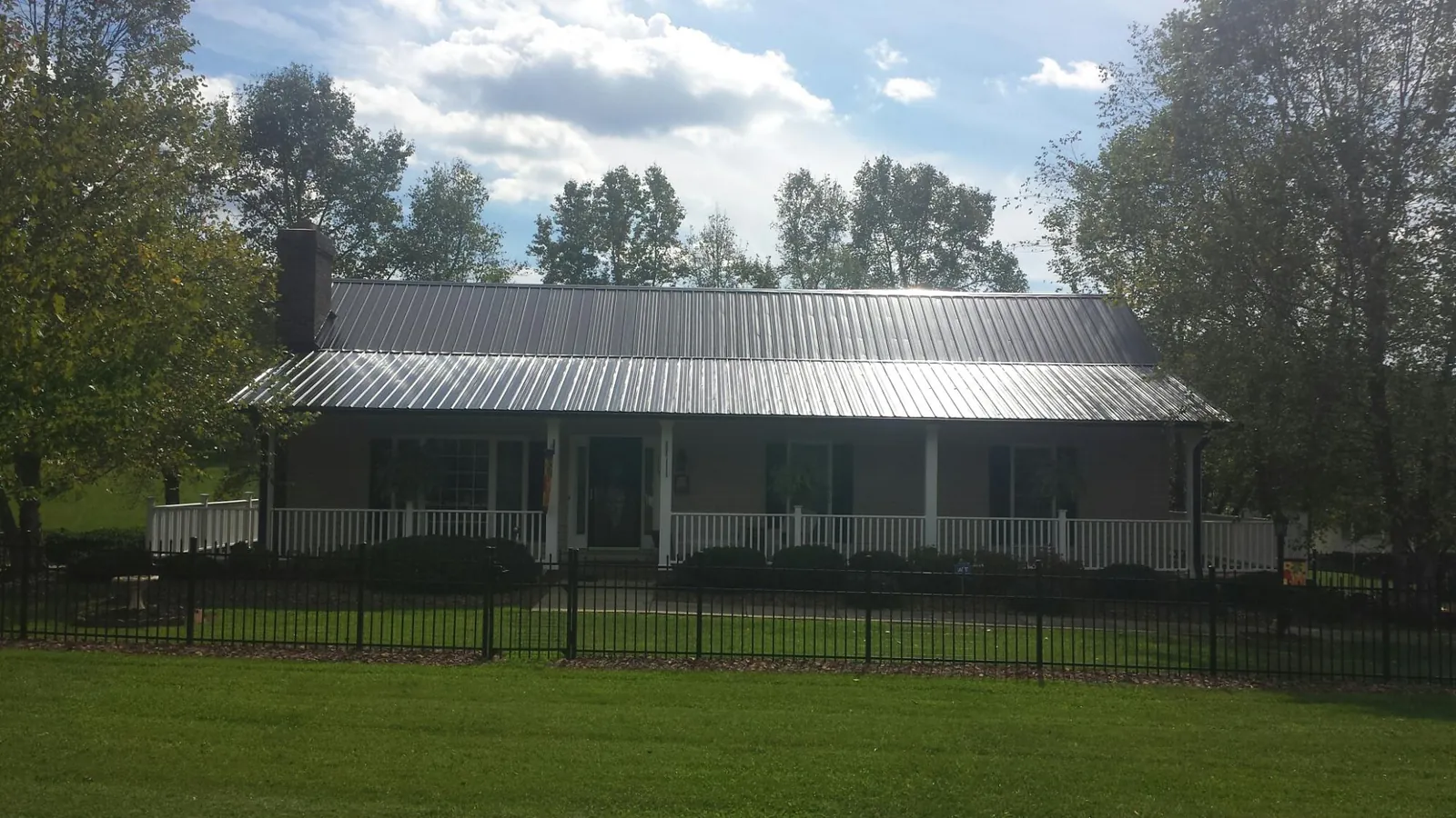 Gray metal roof on a brick ranch with a full width front porch — Gutter Guard Installation work by our crew in Hooversville