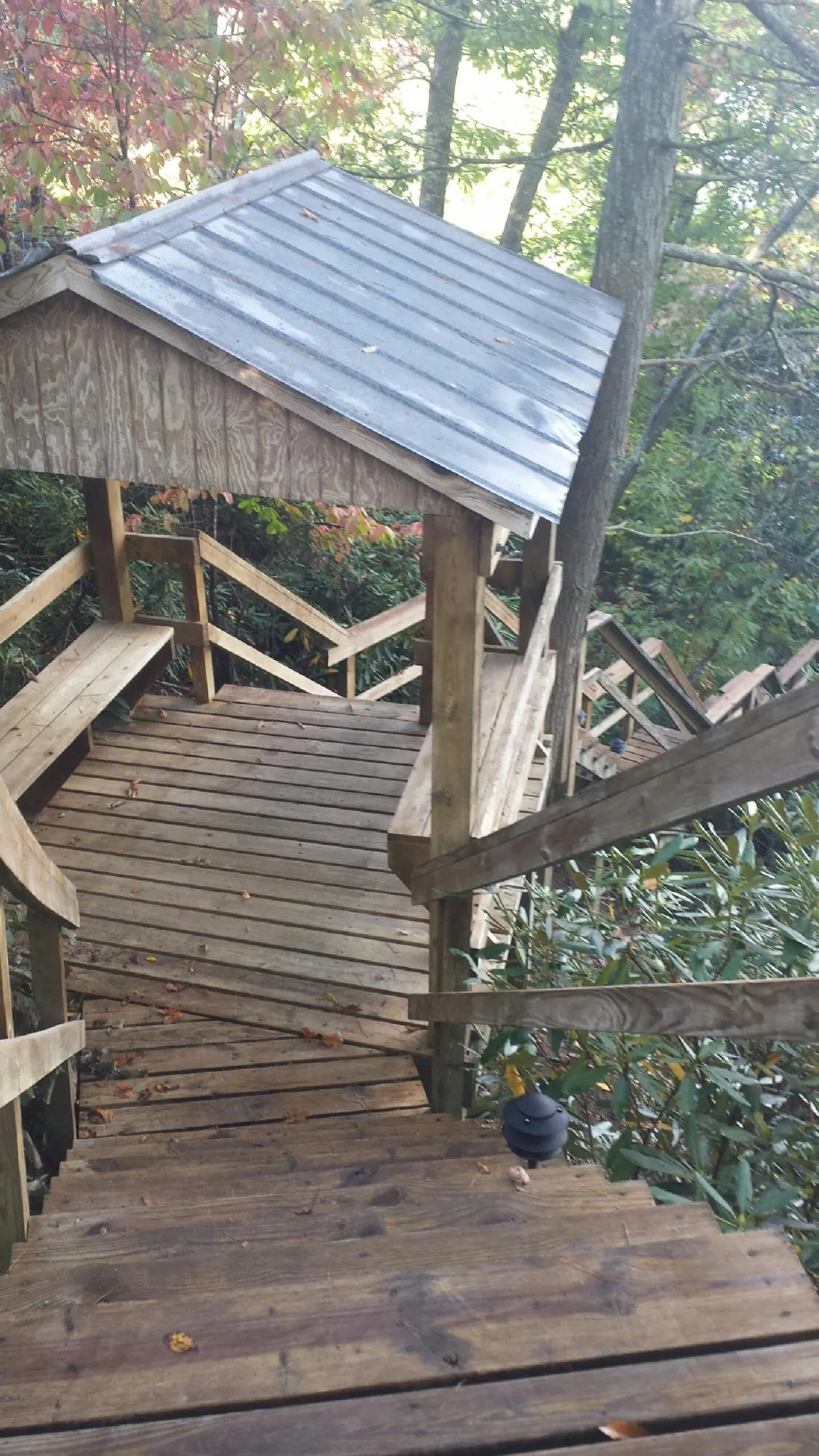 Metal roofed shelter over wooden steps on a wooded walkway — Skylight Repair & Installation work by our crew in Hooversville