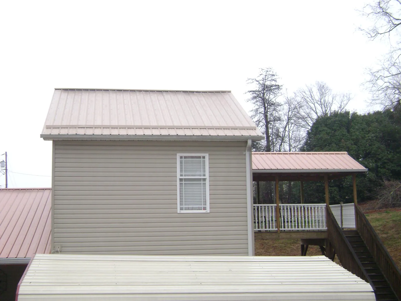 Tan metal roofs on a two story addition and attached porch, from a Roof Replacement job in Hooversville
