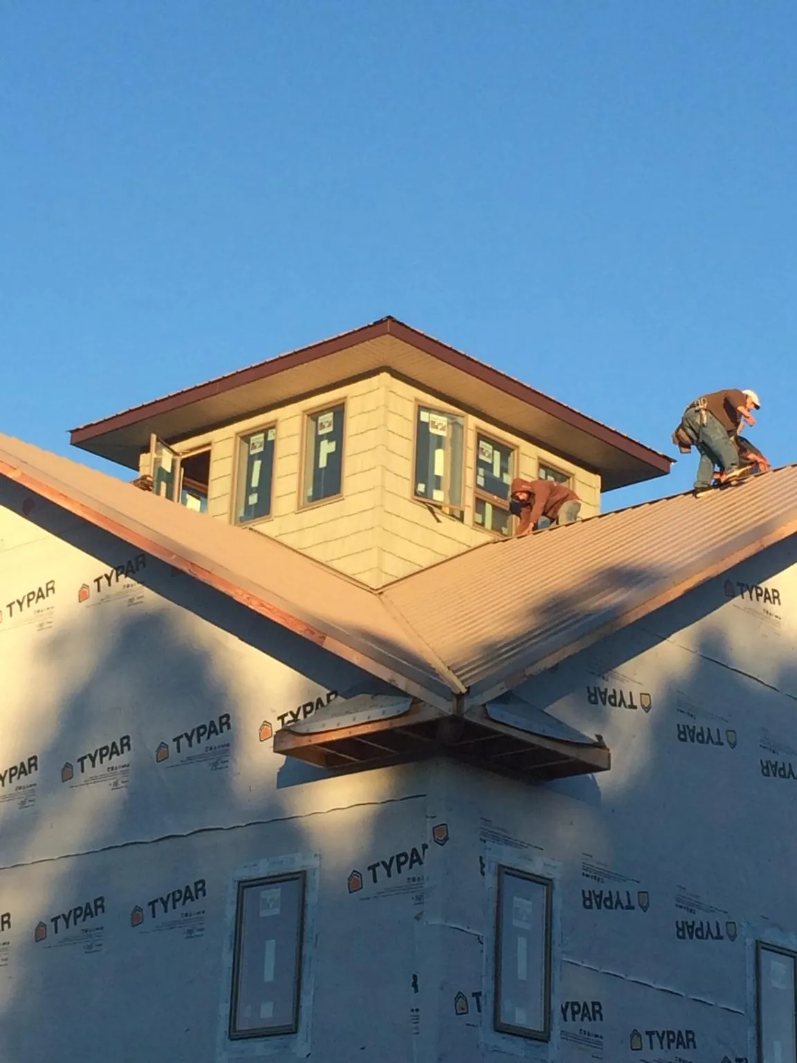 Roofers working around a rooftop cupola on a new metal roof at sunset — Roof Waterproofing in Hooversville by Roofing Brothers